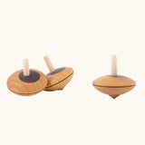 Three Mader Kreiselmanufaktur Wooden Nonna Spinning Tops, one is spinning.