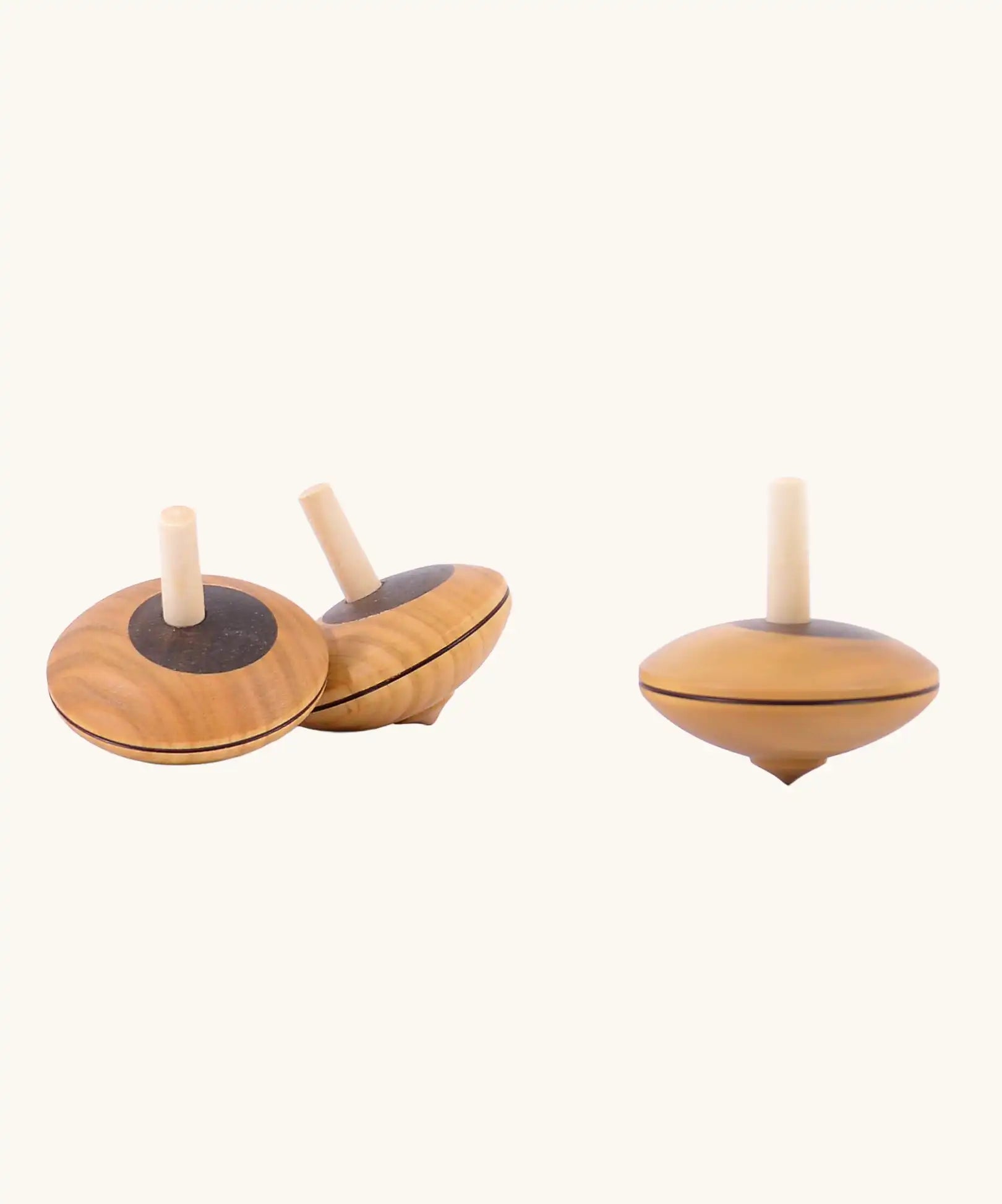 Three Mader Kreiselmanufaktur Wooden Nonna Spinning Tops, one is spinning.