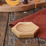 Mader hexagon 8cm spinning top plate in oak placed on a wooden surface.