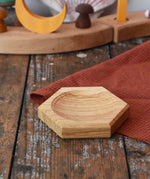 Mader hexagon 8cm spinning top plate in oak placed on a wooden surface.