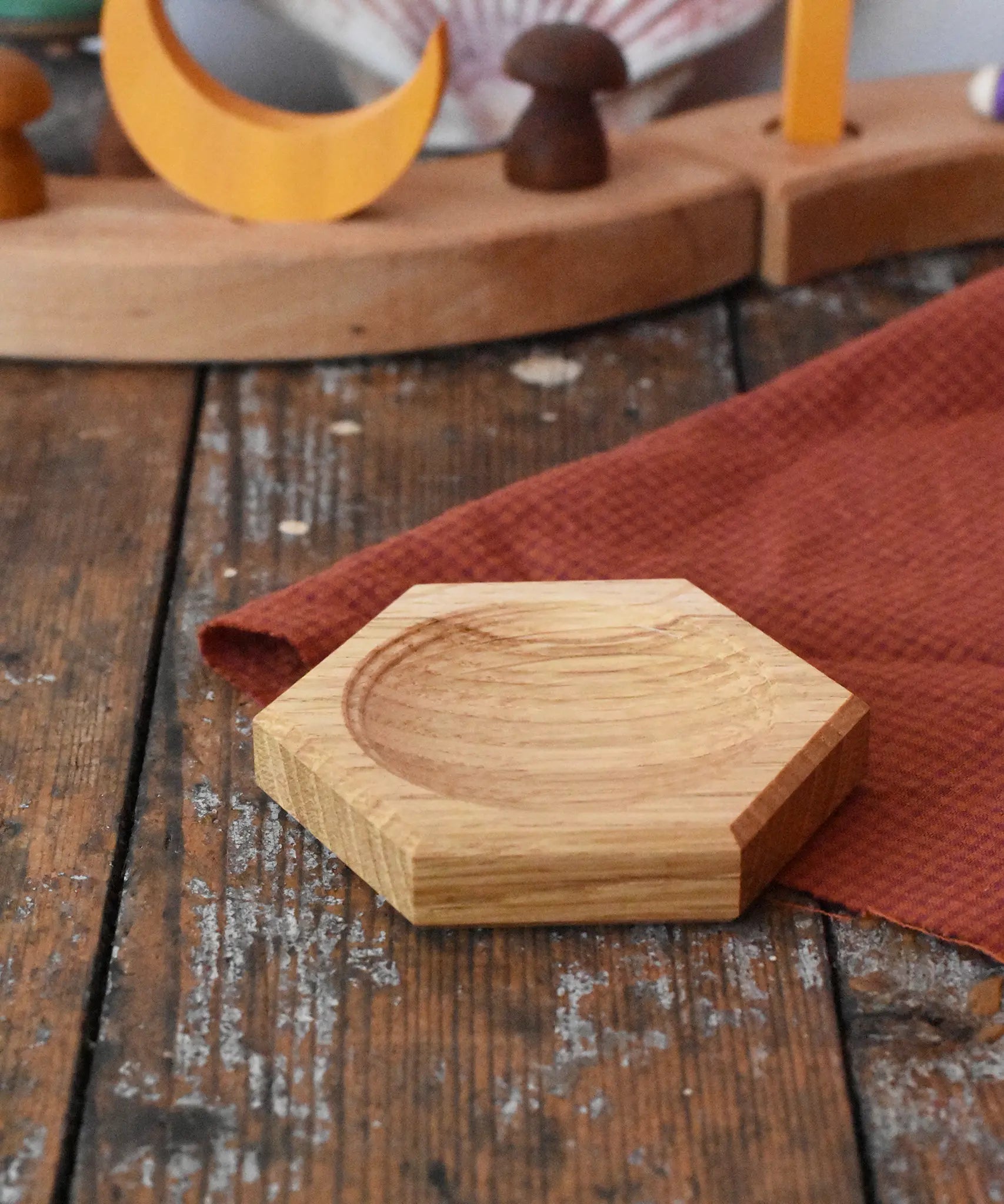 Mader hexagon 8cm spinning top plate in oak placed on a wooden surface.