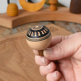 Top of Mader orient turn-over spinning top, held in an adult's hand.