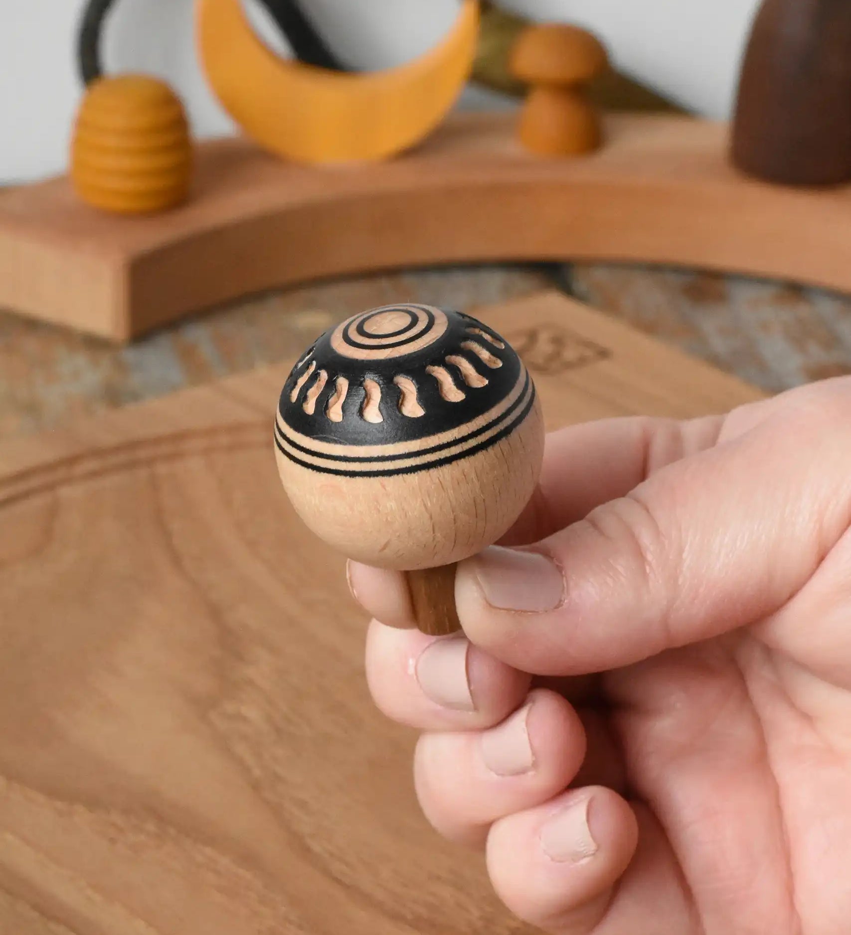 Top of Mader orient turn-over spinning top, held in an adult's hand.