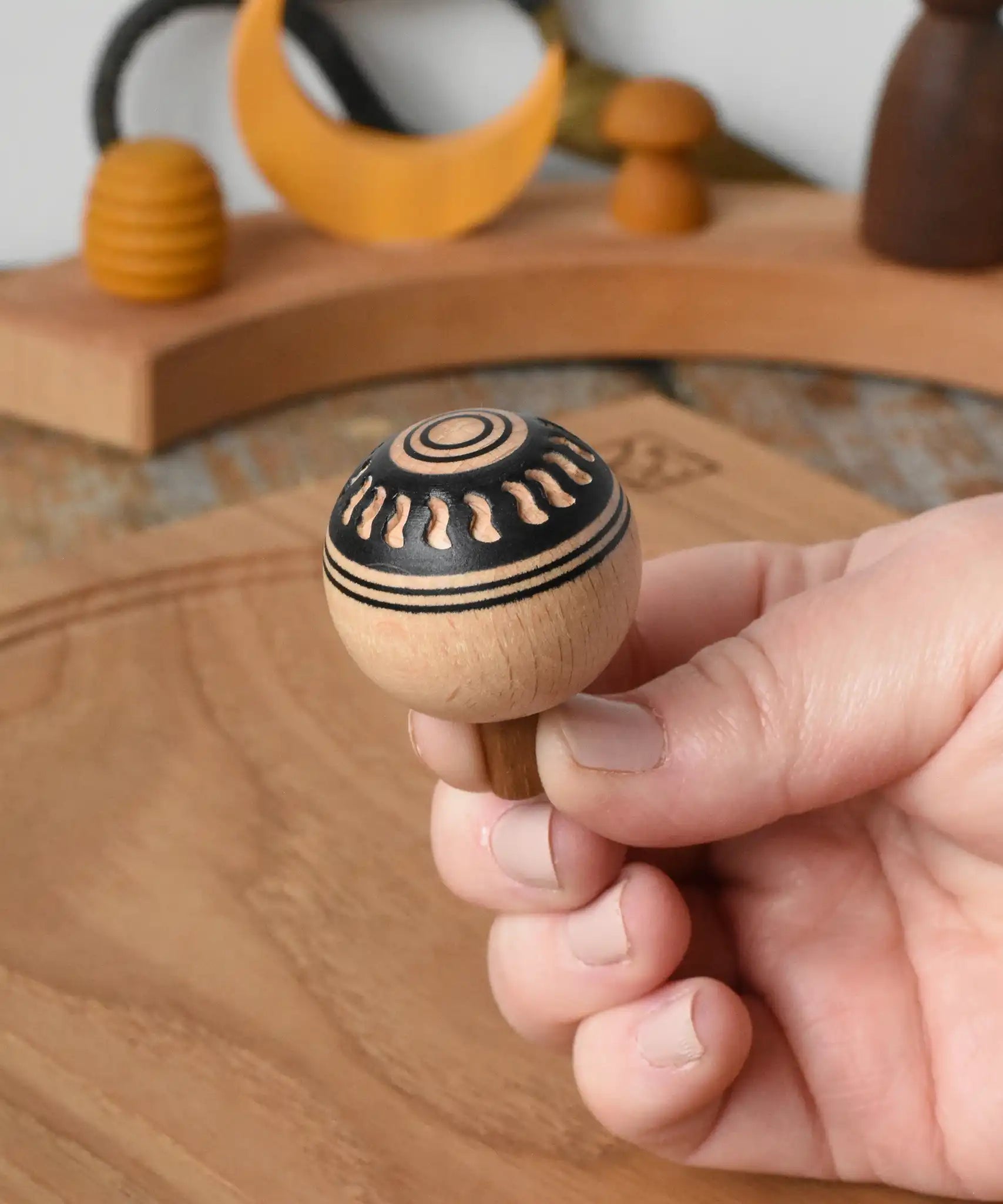 Top of Mader orient turn-over spinning top, held in an adult's hand.