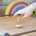 Mader handmade Manege wooden spinning plate on a wooden floor covered in various Mader spinning top toys