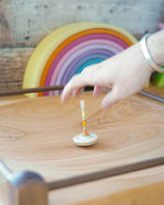 Mader handmade Manege wooden spinning plate on a wooden floor covered in various Mader spinning top toys