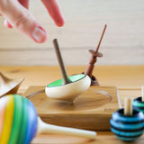 Close up of a hand spinning the Mader handmade wooden zwirbel spinning top on a Mader spinning plate