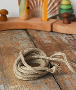 The rope from the Mader natural profi throw spinning top placed on a wooden surface in the Babipur playroom.  