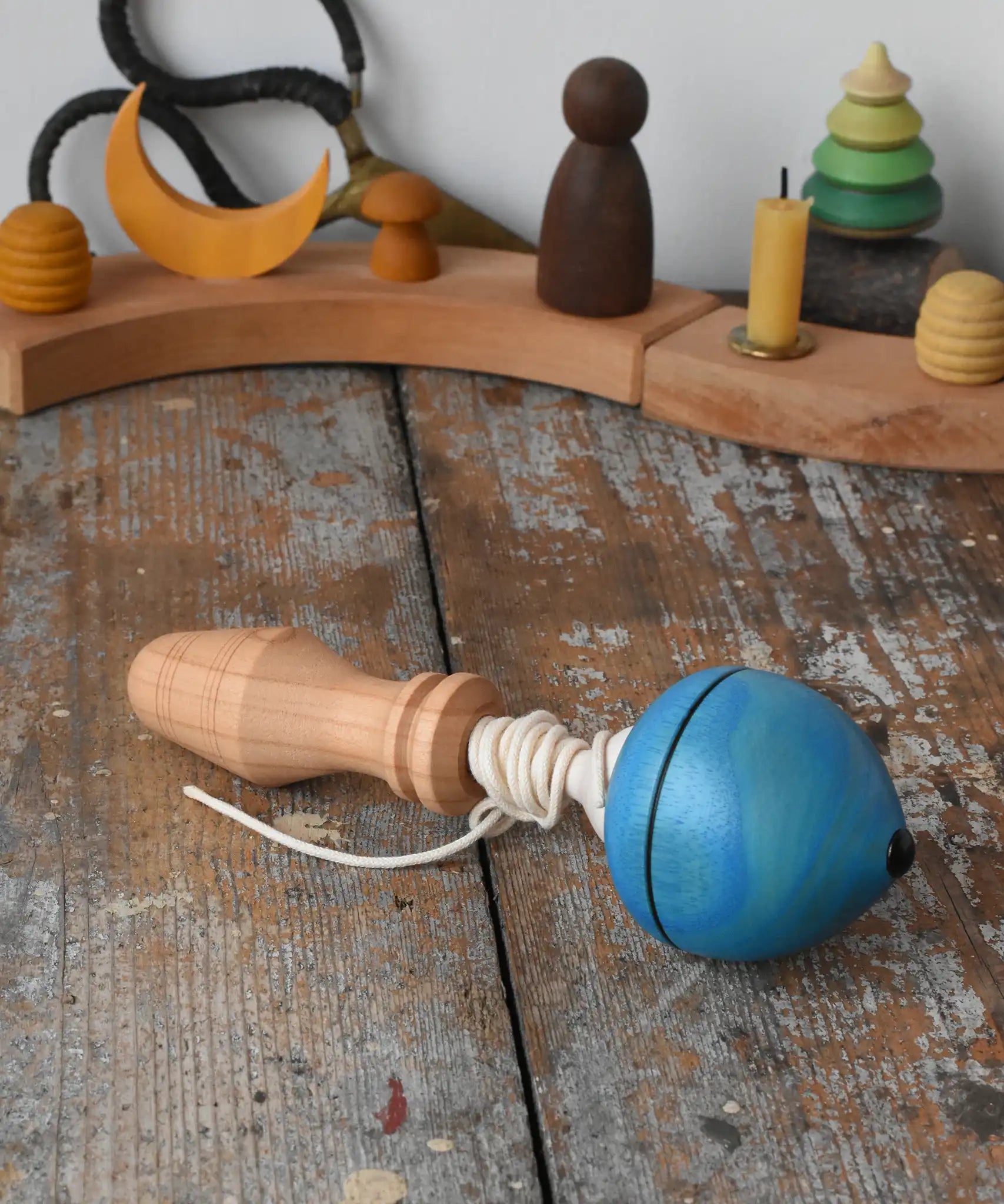 Mader blue pull-string spinning top spinning placed on a wooden surface in the Babipur playroom.