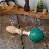 Mader green pull-string spinning top placed on a wooden surface in the Babipur playroom.