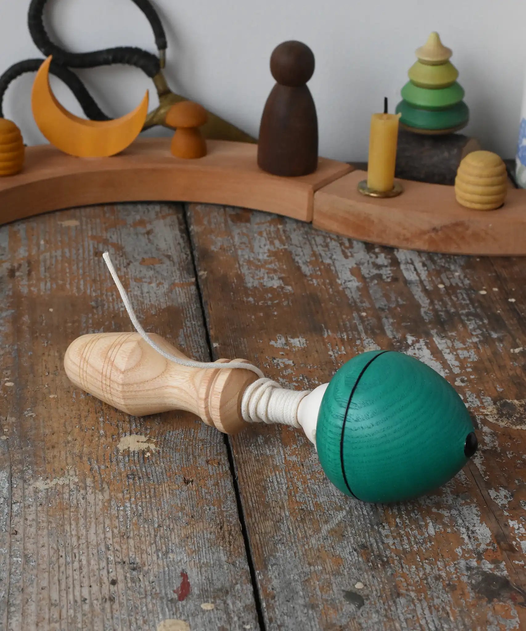 Mader green pull-string spinning top placed on a wooden surface in the Babipur playroom.
