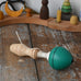Mader green pull-string spinning top placed on a wooden surface in the Babipur playroom.