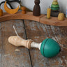 Mader green pull-string spinning top placed on a wooden surface in the Babipur playroom.
