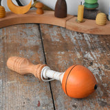 Mader orange pull-string spinning top placed on a wooden surface in the Babipur playroom.