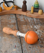 Mader orange pull-string spinning top placed on a wooden surface in the Babipur playroom.