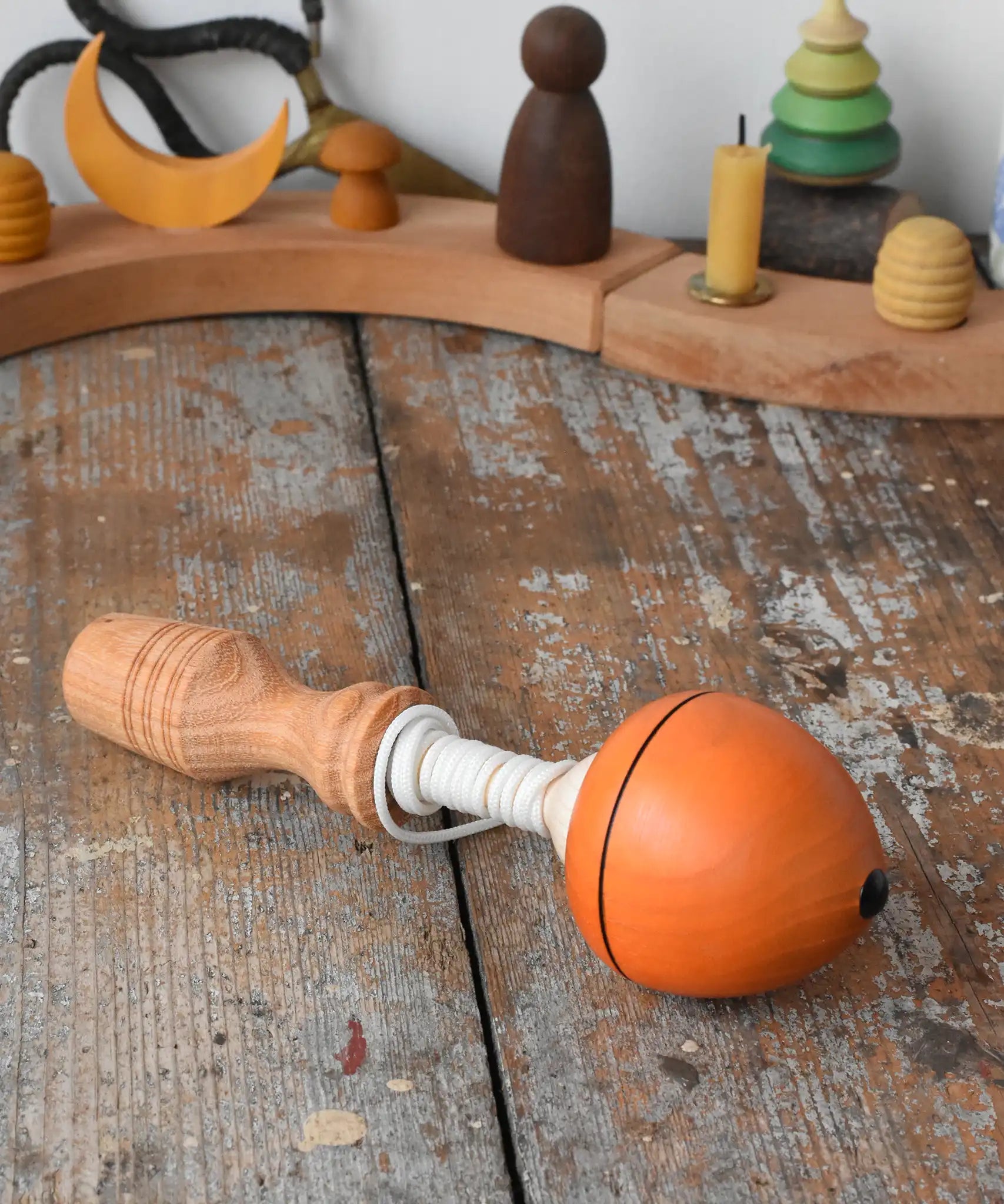 Mader orange pull-string spinning top placed on a wooden surface in the Babipur playroom.