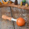 Mader orange pull-string spinning top placed on a wooden surface in the Babipur playroom.
