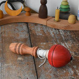 Mader red pull-string spinning top placed on a wooden surface in the Babipur playroom.