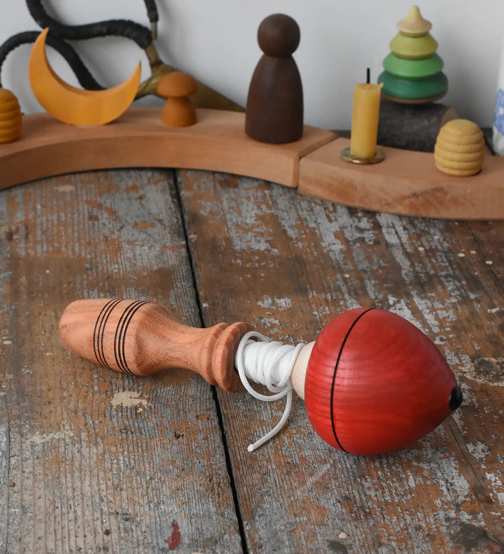 Mader red pull-string spinning top placed on a wooden surface in the Babipur playroom.