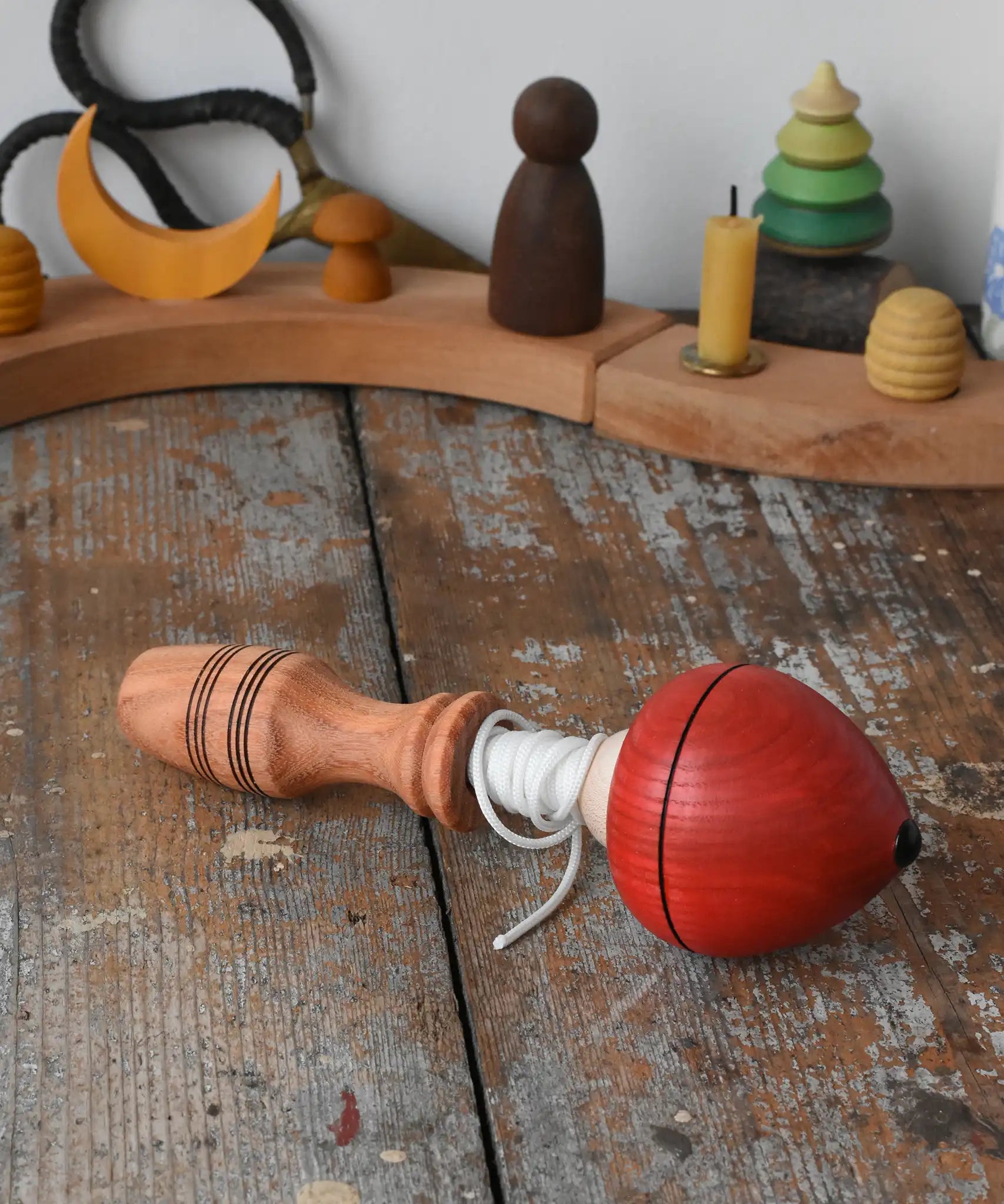 Mader red pull-string spinning top placed on a wooden surface in the Babipur playroom.