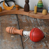 Mader red pull-string spinning top placed on a wooden surface in the Babipur playroom.
