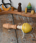 Mader yellow pull-string spinning top spinning placed on a wooden surface in the Babipur playroom.