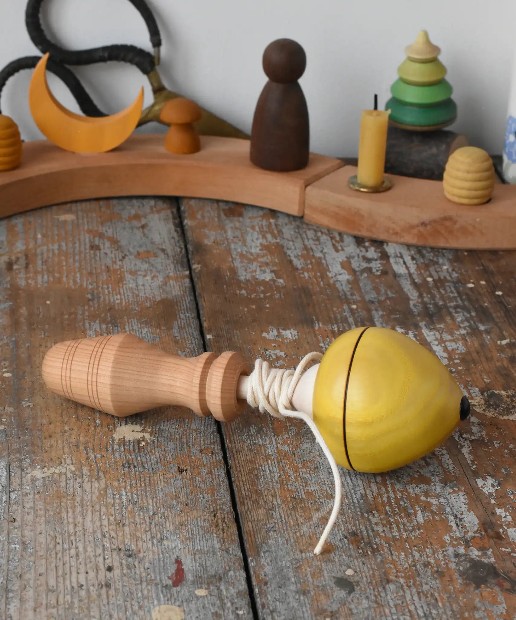 Mader yellow pull-string spinning top spinning placed on a wooden surface in the Babipur playroom.