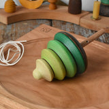 Mader pull-string tree spinning top placed on a cherry wood spinning plate in the Babipur playroom.