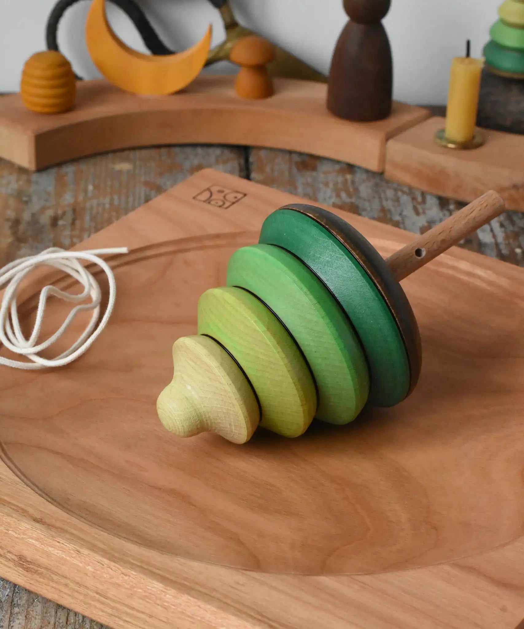 Mader pull-string tree spinning top placed on a cherry wood spinning plate in the Babipur playroom.