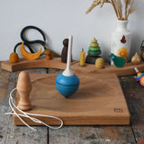 Mader blue pull-string spinning top spinning on a large oak spinning plate in the Babipur playroom.