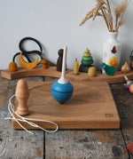 Mader blue pull-string spinning top spinning on a large oak spinning plate in the Babipur playroom.