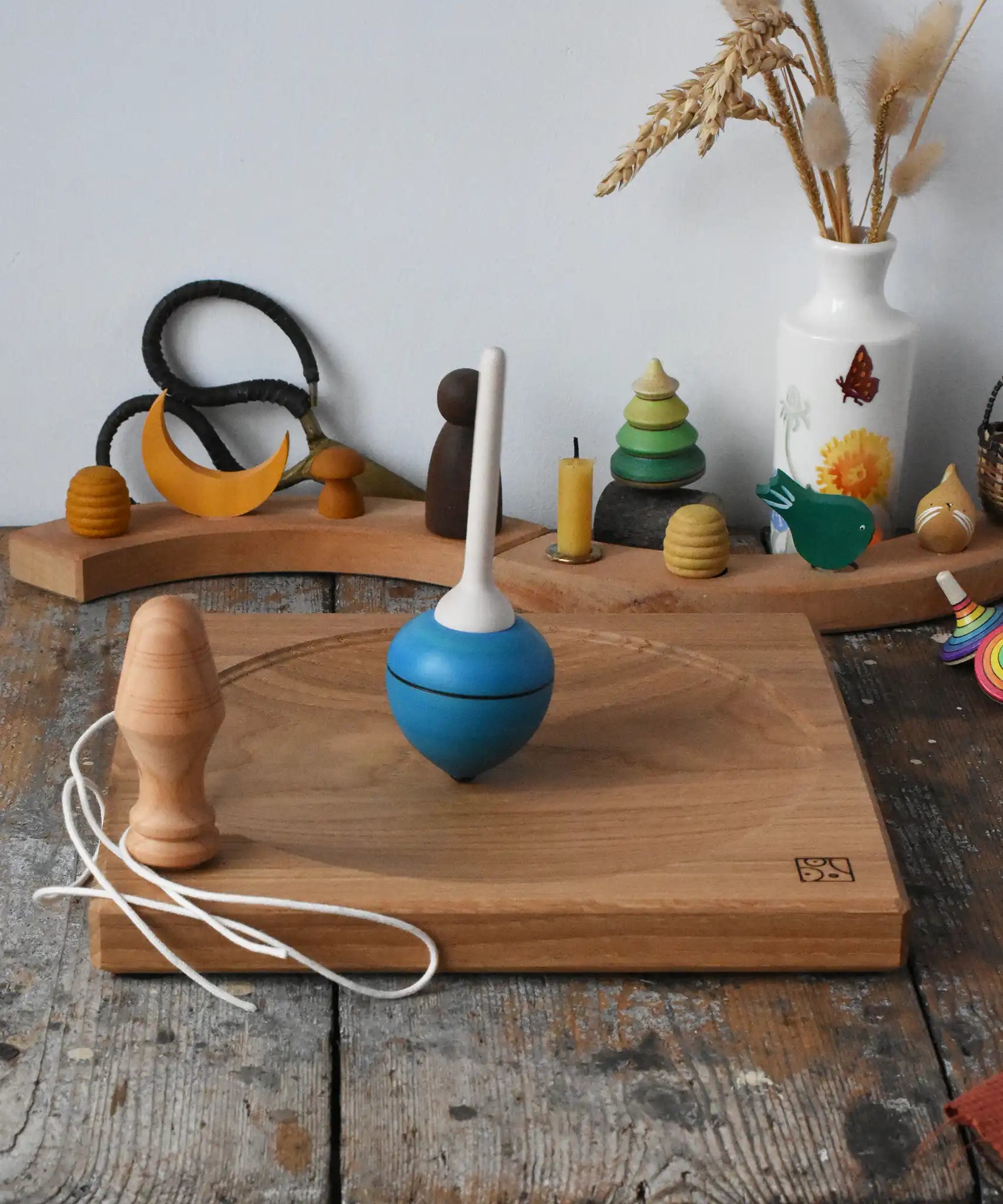 Mader blue pull-string spinning top spinning on a large oak spinning plate in the Babipur playroom.