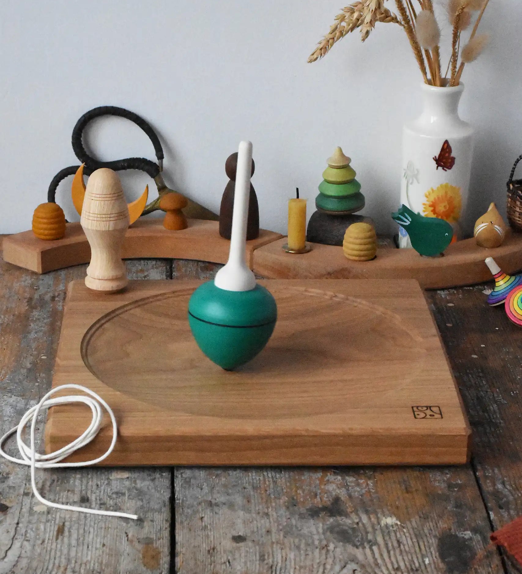 Mader green pull-string spinning top spinning on a large oak spinning plate in the Babipur playroom.