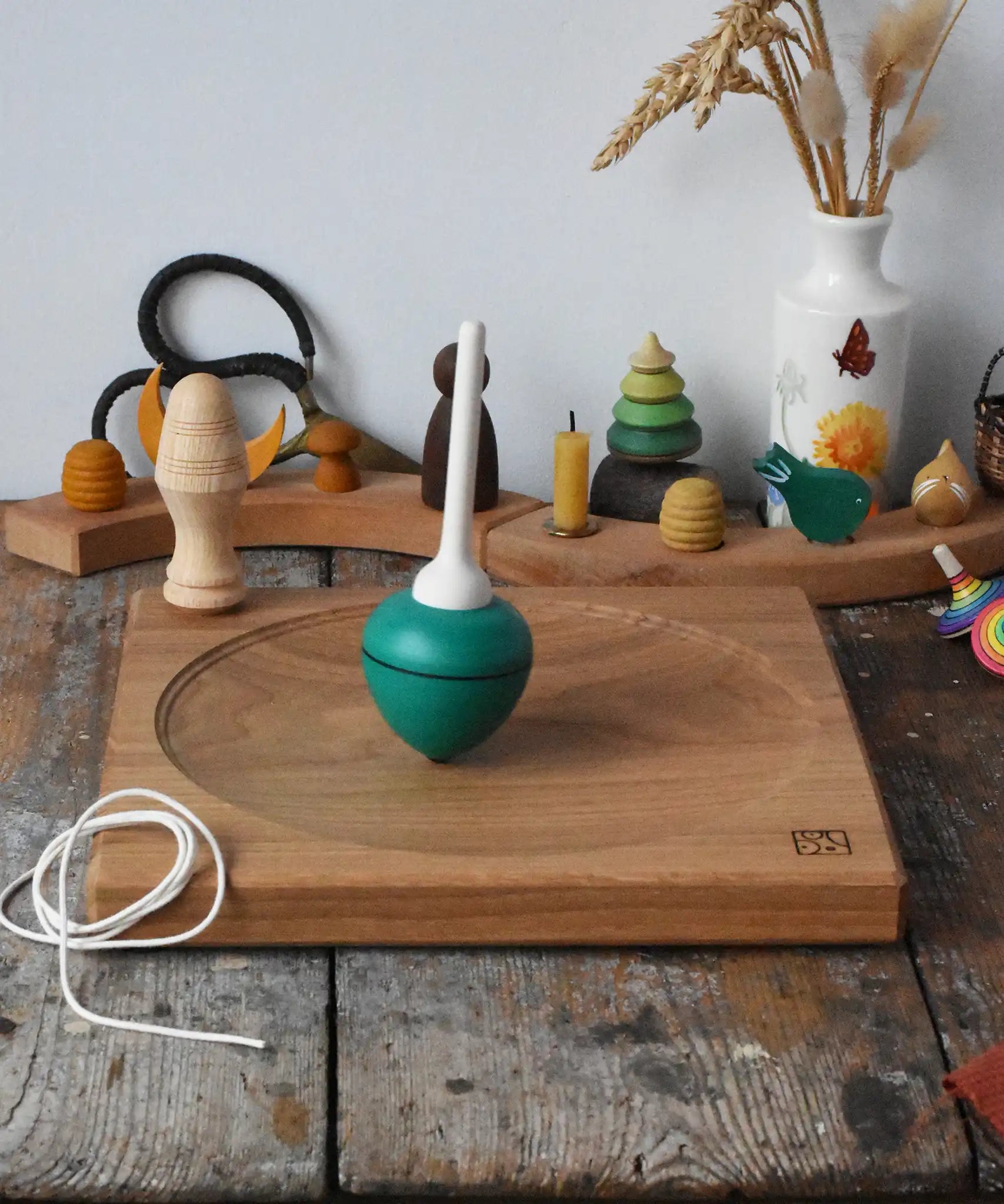 Mader green pull-string spinning top spinning on a large oak spinning plate in the Babipur playroom.