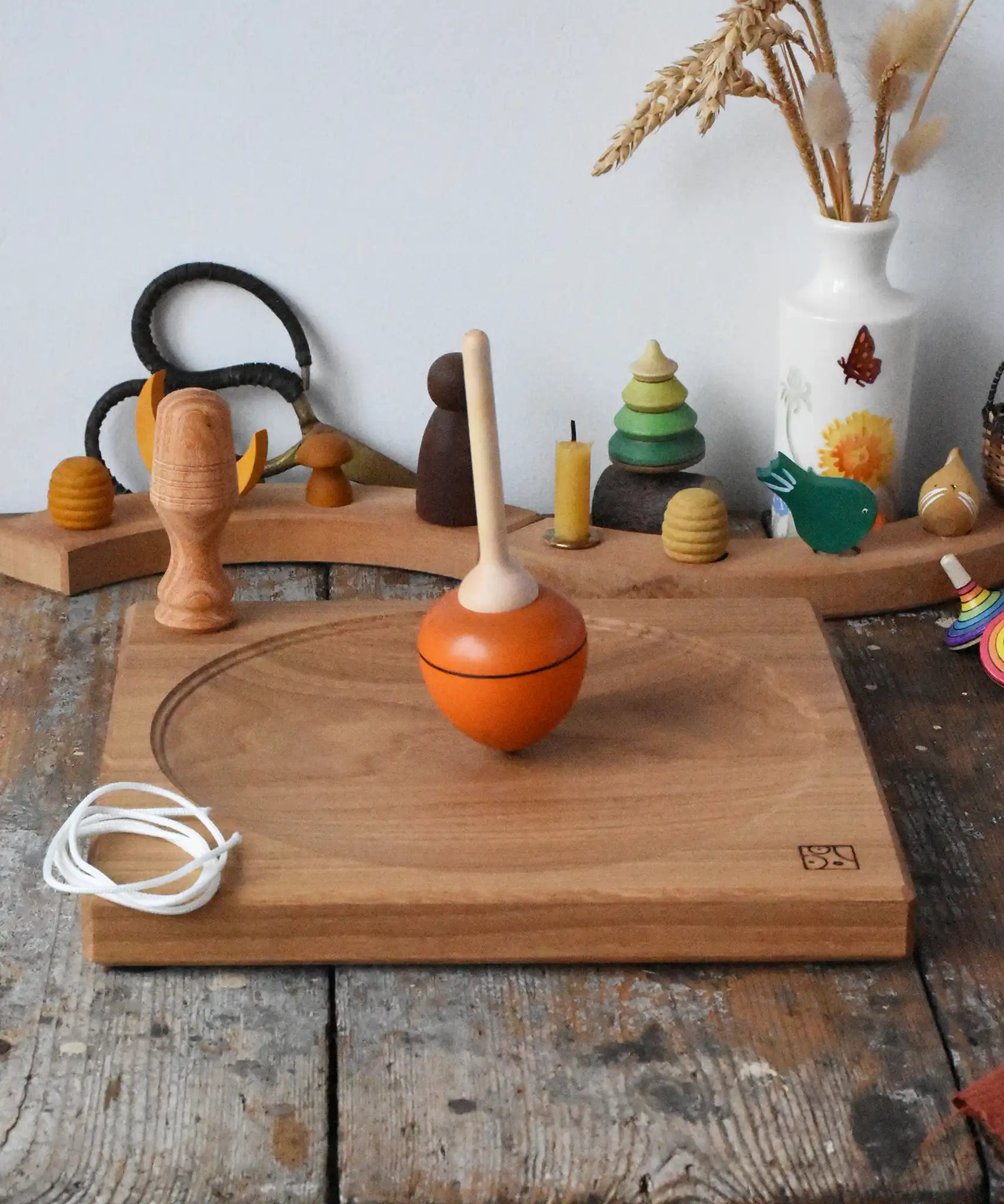 Mader orange pull-string spinning top spinning on a large oak spinning plate in the Babipur playroom.