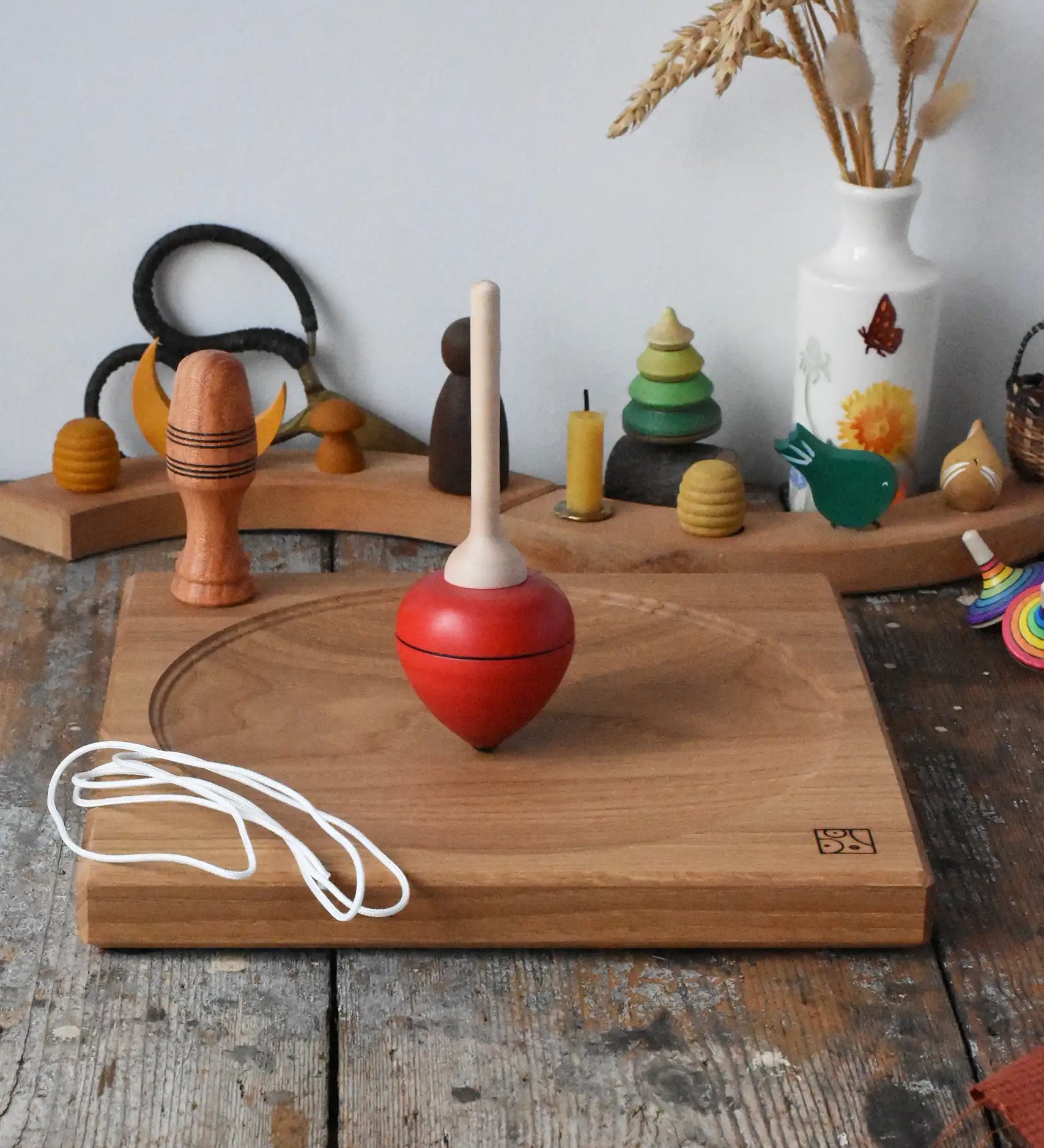 Mader red pull-string spinning top spinning on a large oak spinning plate in the Babipur playroom.