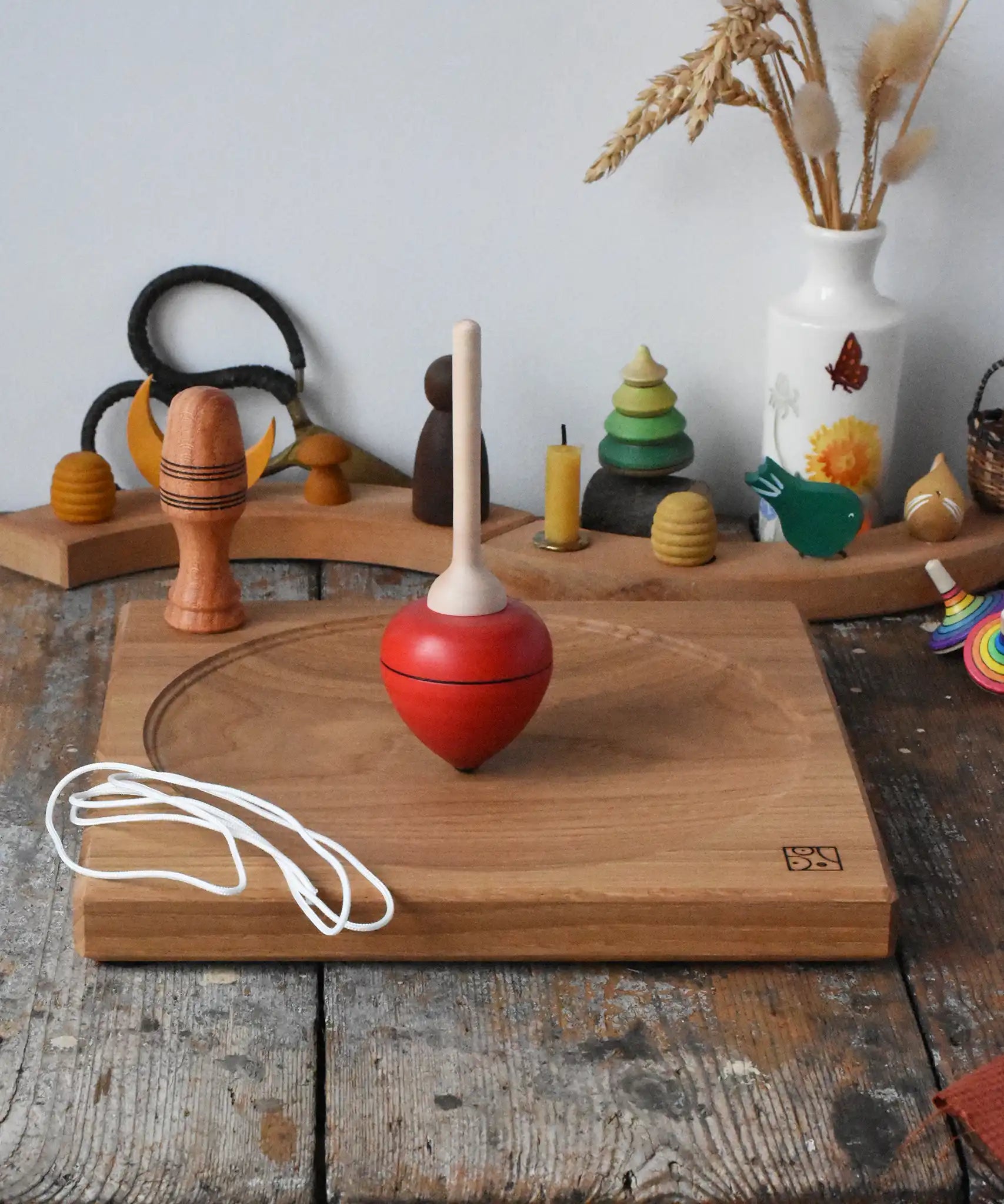 Mader red pull-string spinning top spinning on a large oak spinning plate in the Babipur playroom.