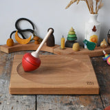 Mader red pull-string spinning top spinning on a large oak spinning plate in the Babipur playroom.