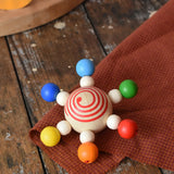 Mader carousel wooden baby grapsing toy placed on a wooden surface.