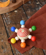 Mader carousel wooden baby grapsing toy placed on a wooden surface.