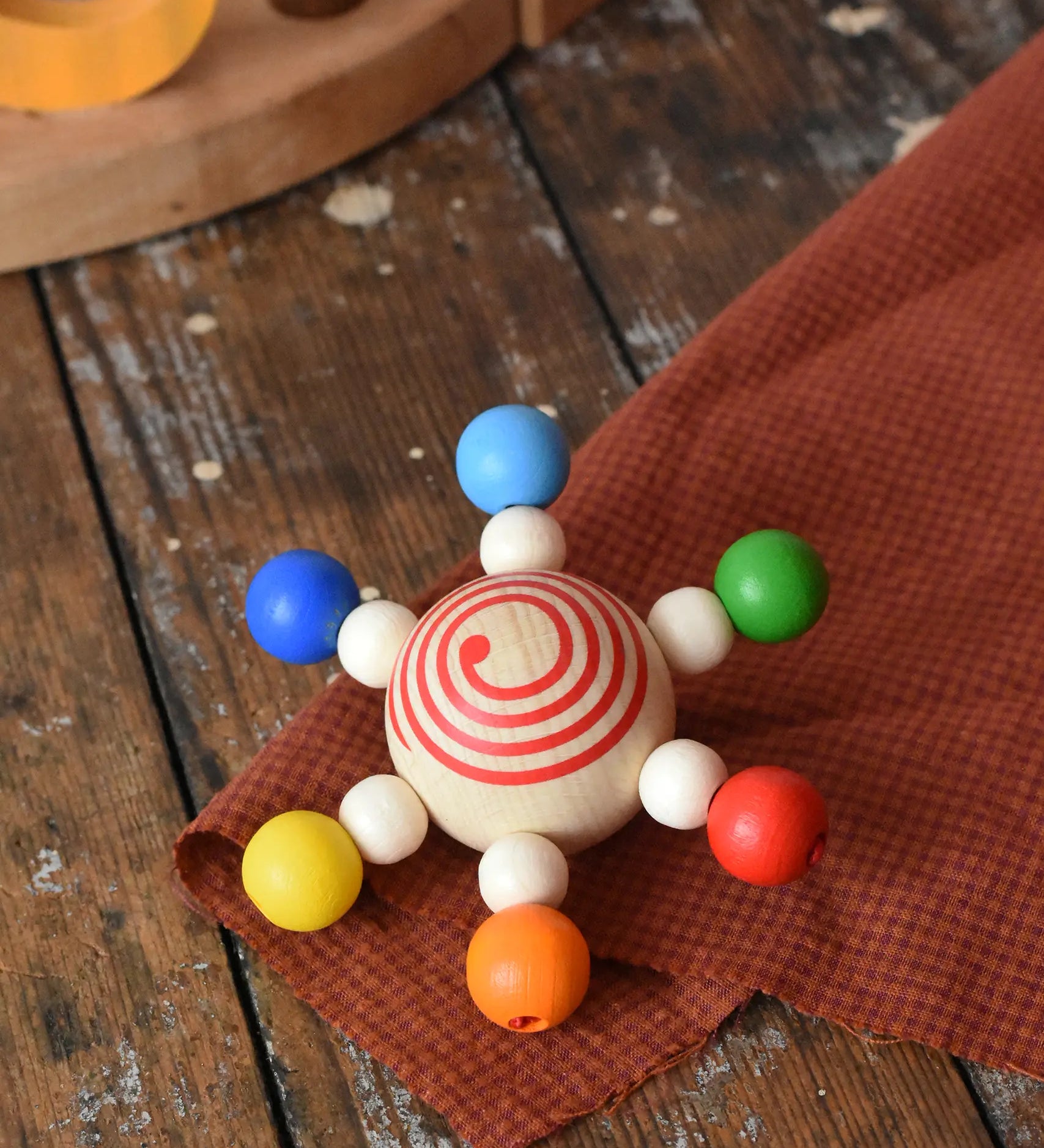 Mader carousel wooden baby grapsing toy placed on a wooden surface.