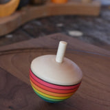 Mader Kreiselmanufaktur rainbow egg spinning top spinning in motion on a walnut wood plate in the Babipur playroom.