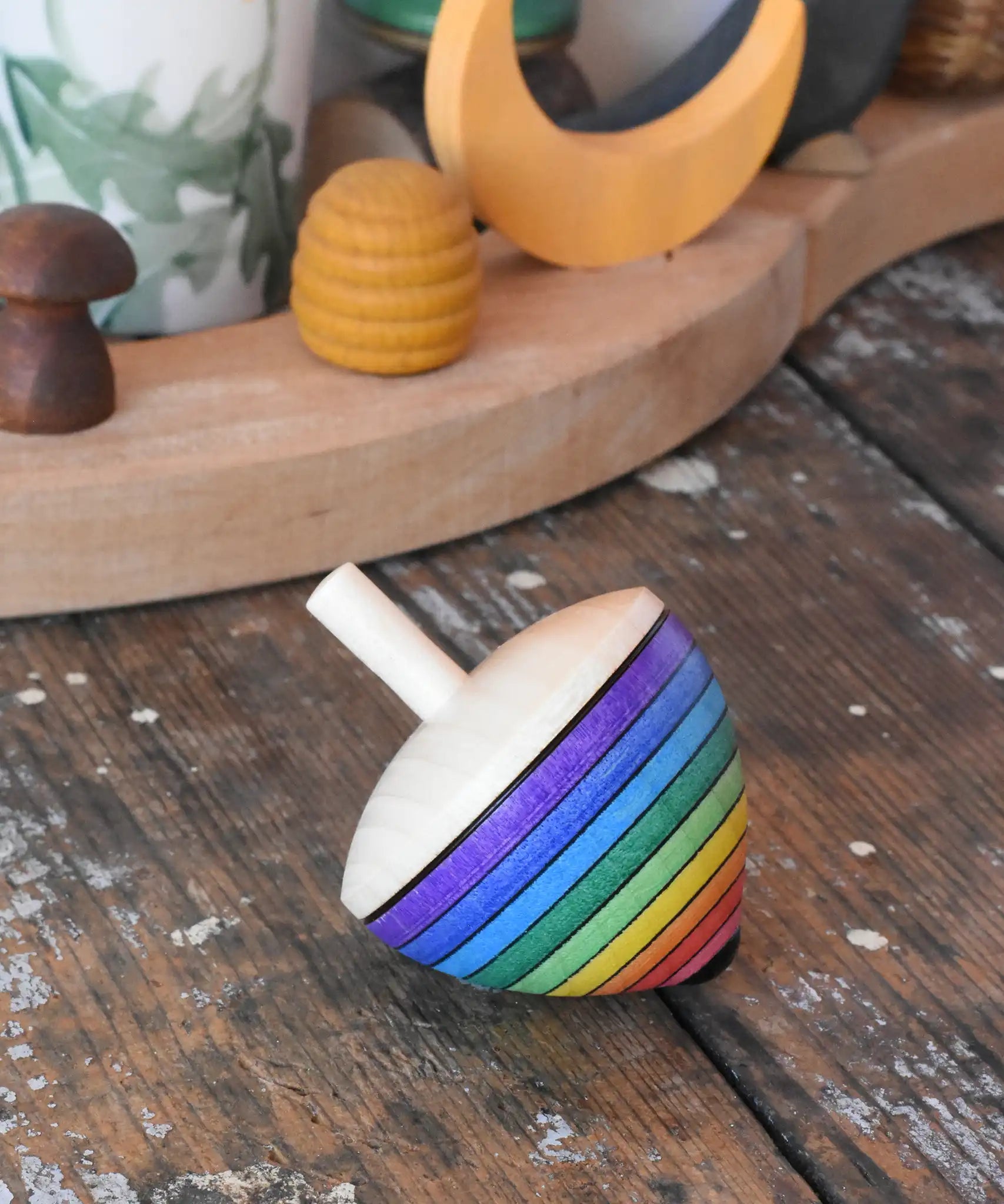 Mader Kreiselmanufaktur rainbow egg spinning top placed on a wooden surface in the Babipur playroom.