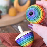 Metal tip on the bottom of a Mader Kreiselmanufaktur rainbow egg spinning top in an adult's hand.