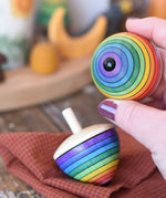Metal tip on the bottom of a Mader Kreiselmanufaktur rainbow egg spinning top in an adult's hand.