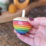 Mader Kreiselmanufaktur rainbow egg spinning top in an adult's hand in the Babipur playroom.