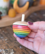 Mader Kreiselmanufaktur rainbow egg spinning top in an adult's hand in the Babipur playroom.