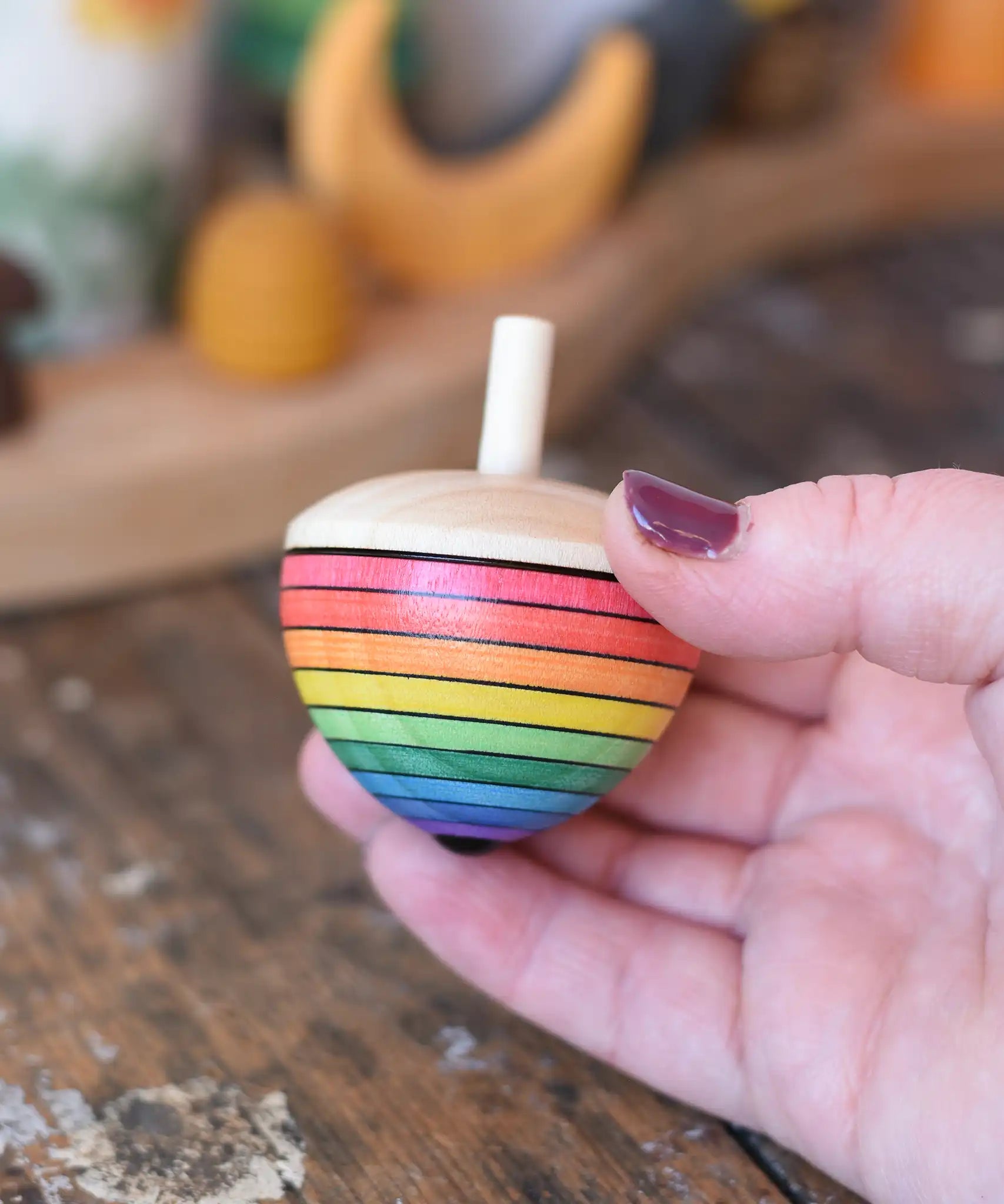 Mader Kreiselmanufaktur rainbow egg spinning top in an adult's hand in the Babipur playroom.