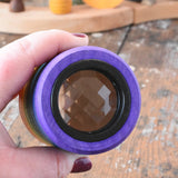 Mader Rainbow Kaleidoscope in an adult hand with the lens side facing the camera. 