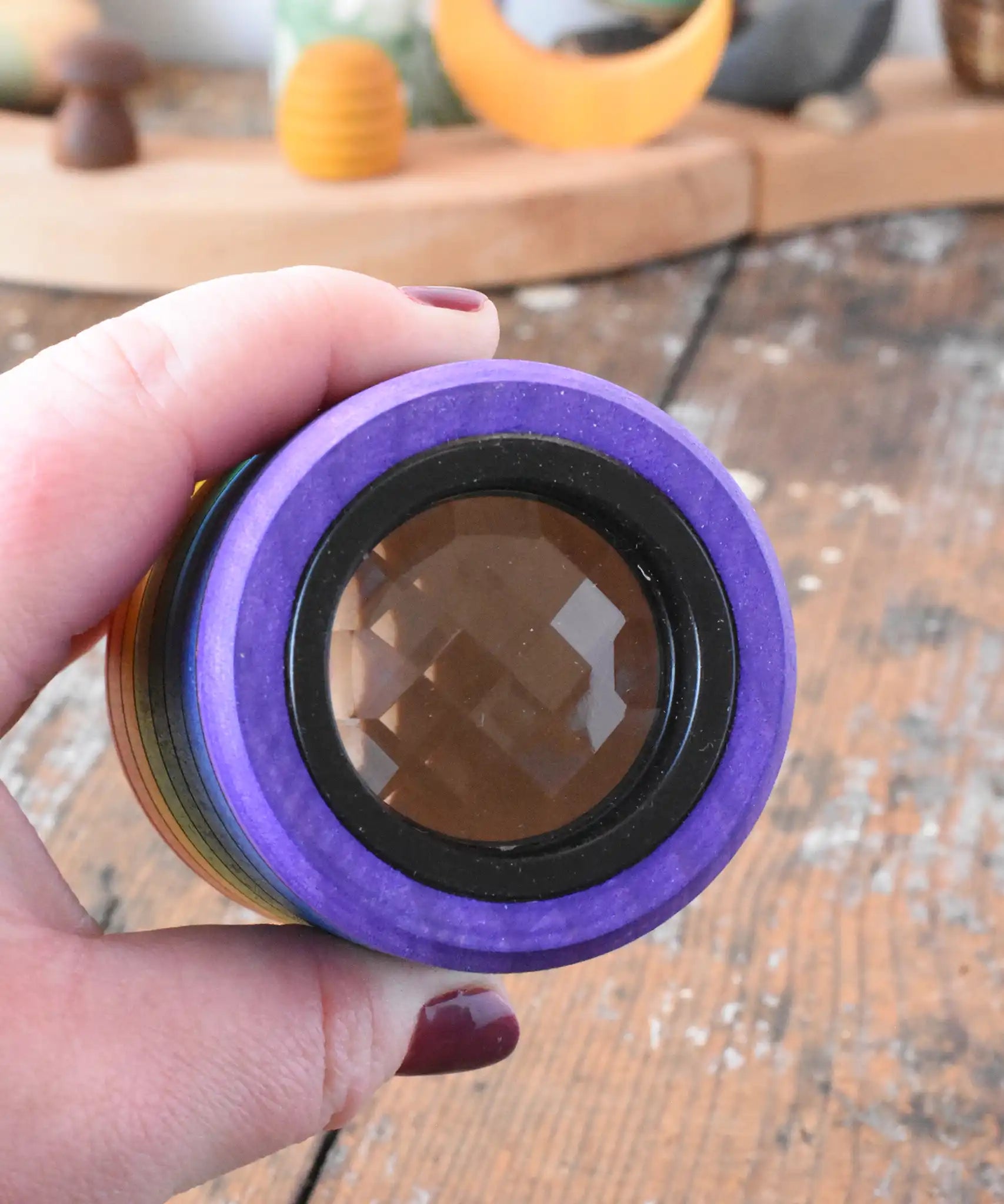 Mader Rainbow Kaleidoscope in an adult hand with the lens side facing the camera. 
